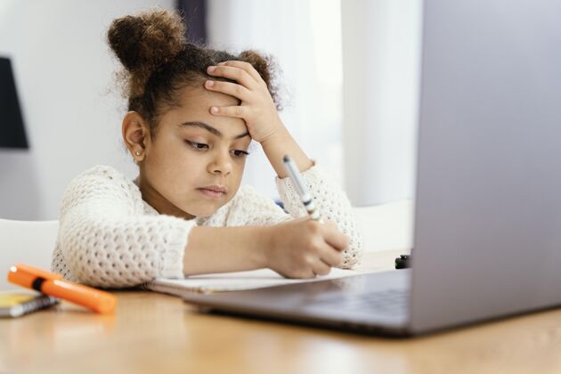 班级侧视图担心的小女孩在家里 在网上学校与笔记本电脑年轻学校课程