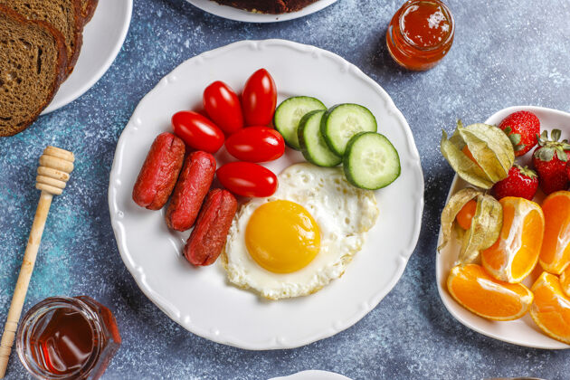 午餐早餐盘子里有鸡尾酒香肠 煎蛋 樱桃番茄 糖果 水果和一杯桃子汁饮料蔬菜顶部