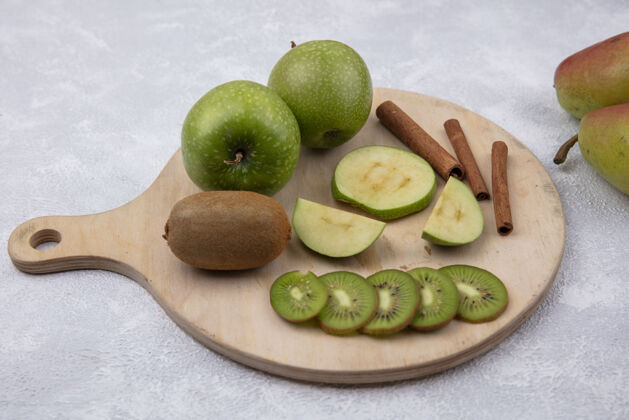 立场侧视图绿色苹果与猕猴桃和肉桂片的立场上的白色背景白色食品壁板