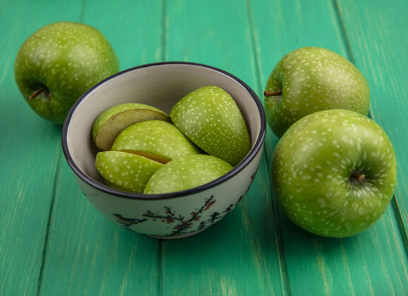 水果前视图绿色苹果片在碗与整个绿色背景新鲜苹果正面