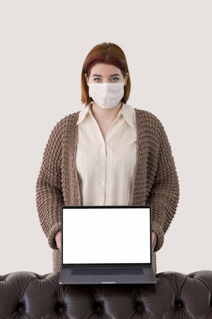 面具戴着面具拿着笔记本电脑的女人的前视图感染女人流行病