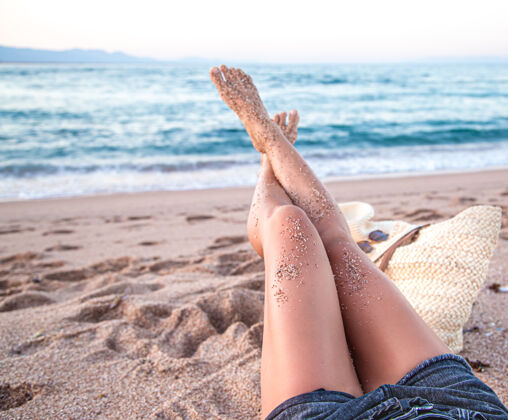 休息身体的一部分女性的脚在沙滩上靠近海边的沙滩上女孩美腿减肥