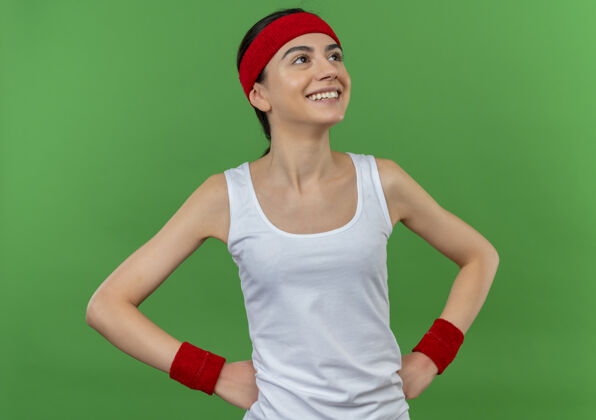 运动身穿运动服 头戴花环 面带微笑 自信地站在绿墙上的年轻健身女士长相健身微笑