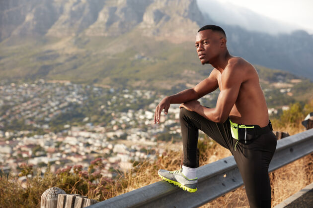 慢跑运动男镜头 皮肤黝黑健康 运动后休息 在交通标志上抬腿 表情周到 在山上摆姿势 喜欢户外运动慢跑理念物理热身活跃