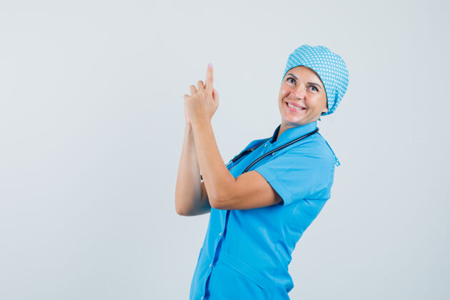治疗身着蓝色制服的女医生正在做手指的招牌 看上去很欢快 正前方视图诊所预防职员