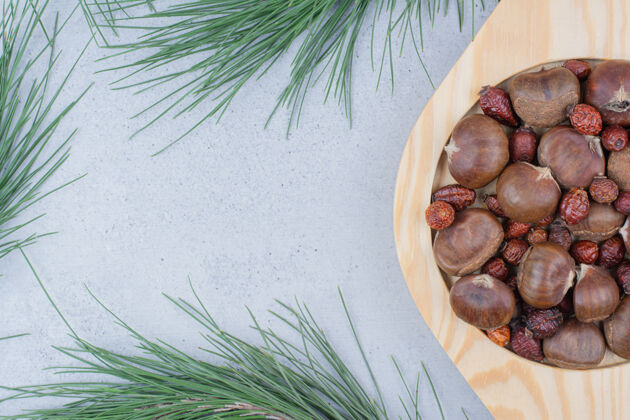 小吃板栗和干玫瑰果放在木盘上栗子新鲜自然