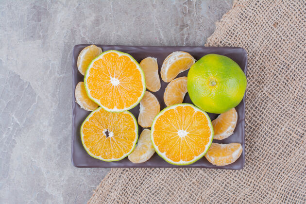 柠檬在黑盘子上放一堆橘子片和橘子片柑橘切片粗麻布