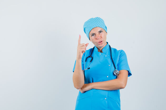 成人穿着蓝色制服的女医生用手指警告 看起来很生气 正面视图女人年轻疾病