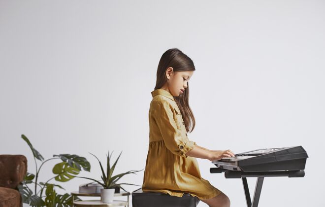 年轻小女孩正在学习如何玩电子键盘音乐家艺术家学习