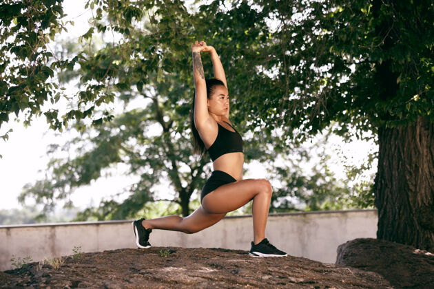 肌肉一个肌肉发达的女运动员在公园里锻炼体操 训练 健身锻炼 柔韧性夏日城市在阳光明媚的日子背景场上积极健康的生活方式 青春 健美身体户外年轻
