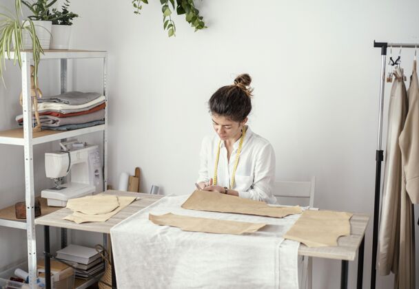 缝纫工艺女裁缝在工作室工作的正面图缝纫昂贵的女士