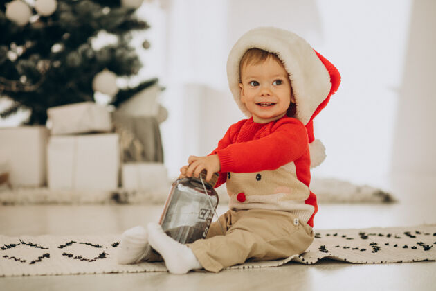 兴奋戴圣诞帽的可爱男孩在圣诞节打开礼物惊喜礼物婴儿