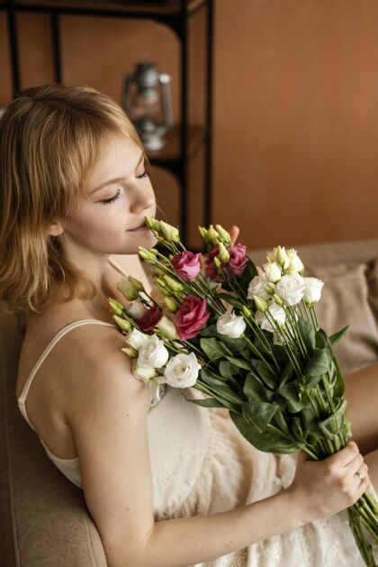 女性美丽的女人拿着一束春花在沙发上摆姿势季节春天垂直