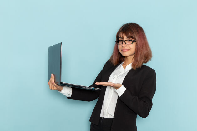 前面正面图女上班族拿着笔记本电脑 在蓝色的表面上微笑女性工作办公室