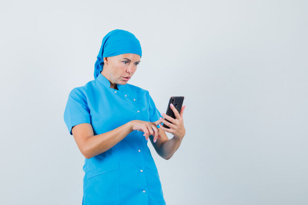 制服穿着蓝色制服的女医生正在用手机 看上去很惊讶治疗手机诊所