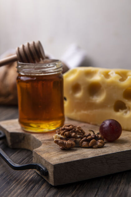天然侧视图蜂蜜与奶酪和核桃在一个罐子里的立场壁板奶酪风景