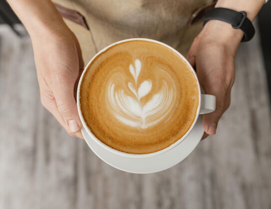 工作女咖啡师手持装饰过的咖啡杯俯视图就业服务员咖啡店