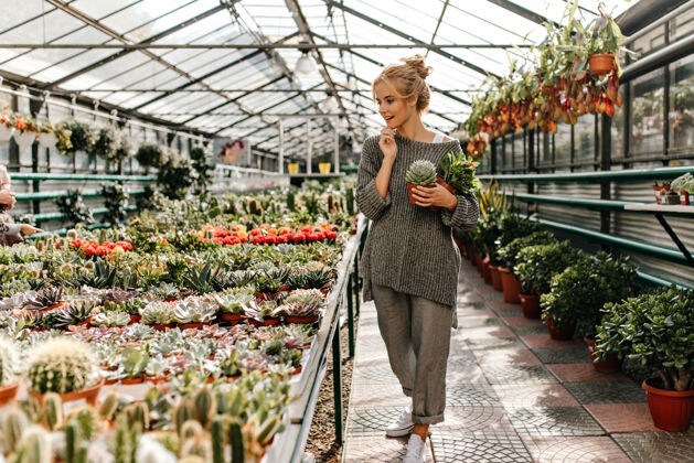 植物穿着宽松时髦的裤子和毛衣的漂亮女人选择植物作为居所 保持多汁积极花店自然