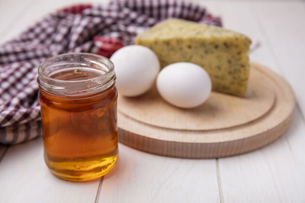 视图前视图蜂蜜在一个罐子里 奶酪和鸡蛋放在一个白色背景的架子上正面鸡蛋奶酪