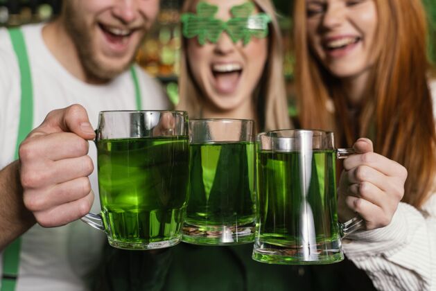 男士一群朋友在酒吧用饮料庆祝圣帕特里克节的前视图酒吧3月17日场合