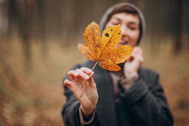 欢呼秋天公园里的年轻女子 捧着树叶的脸服装年轻脸