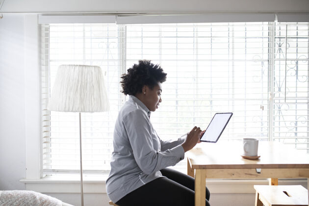 女人在新常态下 一个在数字平板电脑上工作的女人呆在家里远程工作冠状病毒