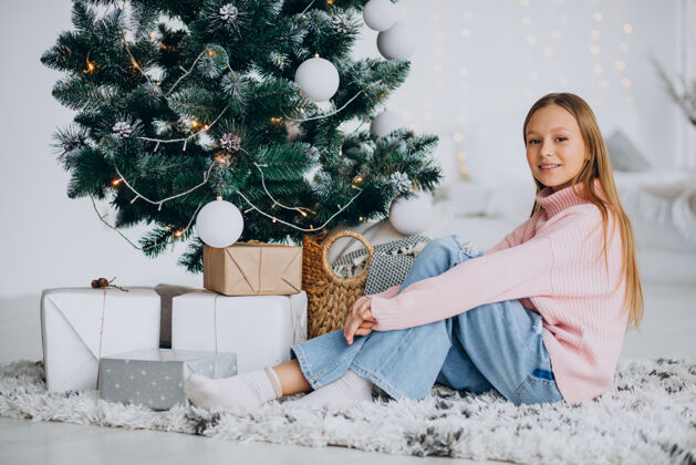 坐着坐在圣诞树旁的小女孩欢乐可爱圣诞老人
