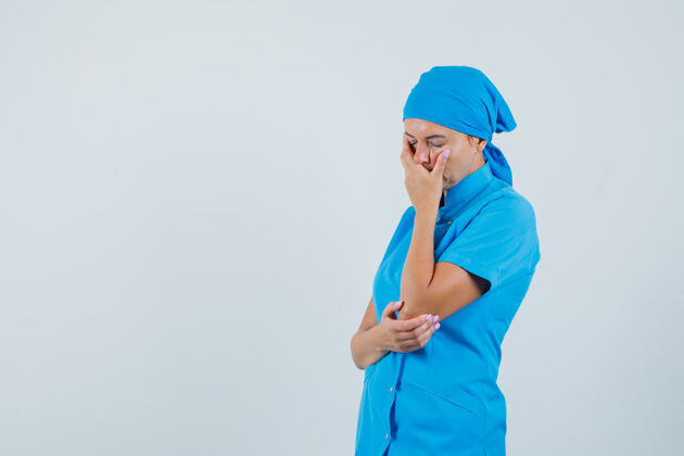 诊断女医生手放在脸上 穿着蓝色制服 面带愁容 俯视前方保存疾病制服