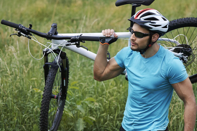 举行身材很好的人拿着他的自行车自行车运动头盔运动员