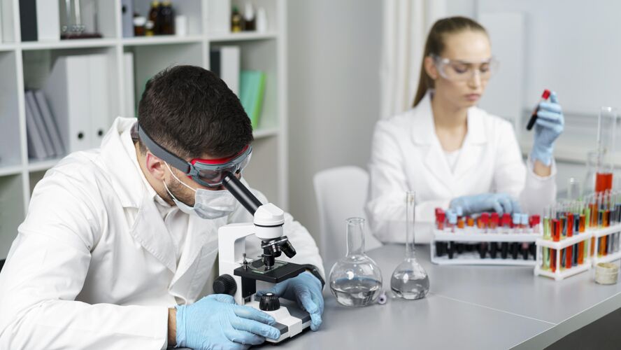 开拓者实验室里的女研究员和男同事拿着试管和安全眼镜女试管专家