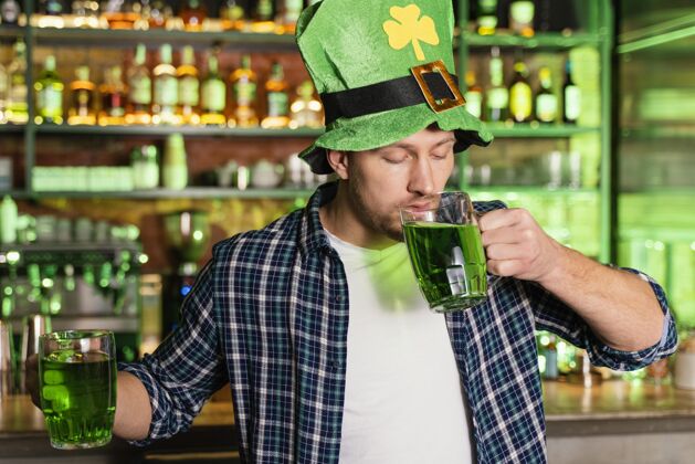 男人在酒吧庆祝圣帕特里克节的男人的正视图幸运绿色饮料