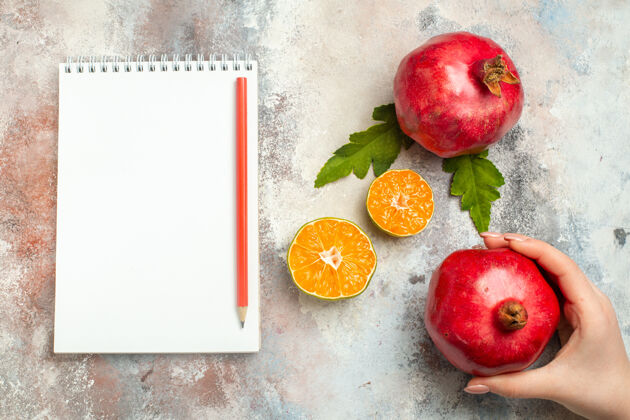 苹果顶视图红色石榴柠檬片红色铅笔笔记本上裸体表面切片多汁维生素