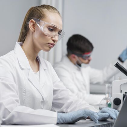 科学家实验室里戴着安全眼镜的女研究员的侧视图创新技术员显微镜