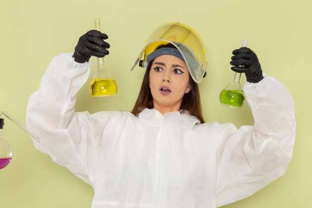 实验室前视图穿着特殊防护服的女化学家在绿色表面上处理溶液特殊化学科学