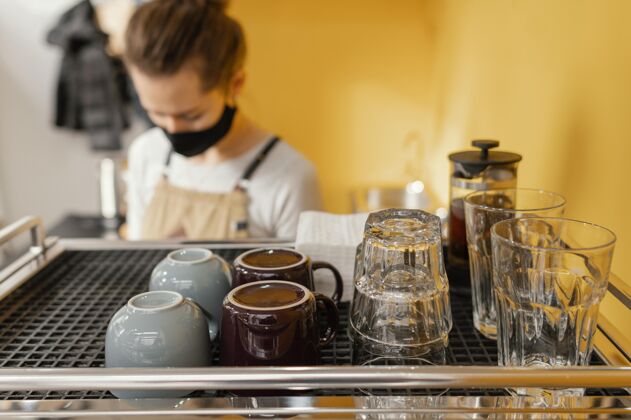 雇员戴着面具的女咖啡师在咖啡店工作咖啡馆横向女
