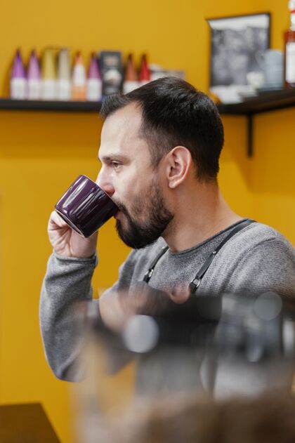 服务员男咖啡师喝咖啡的侧视图专业咖啡店职业