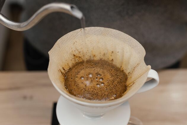 水平高角度的男咖啡师在咖啡过滤器上倒热水咖啡店职业咖啡馆