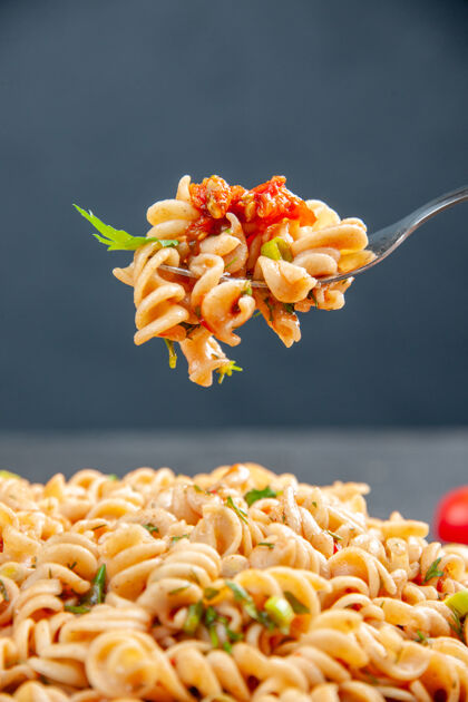 意大利面前视图罗蒂尼面食在盘子和叉子上黑暗的孤立表面花花瓣盘子