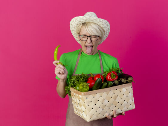短一位年轻的园丁 围着围裙 戴着帽子 手里拿着装满蔬菜的箱子辣椒抱年轻