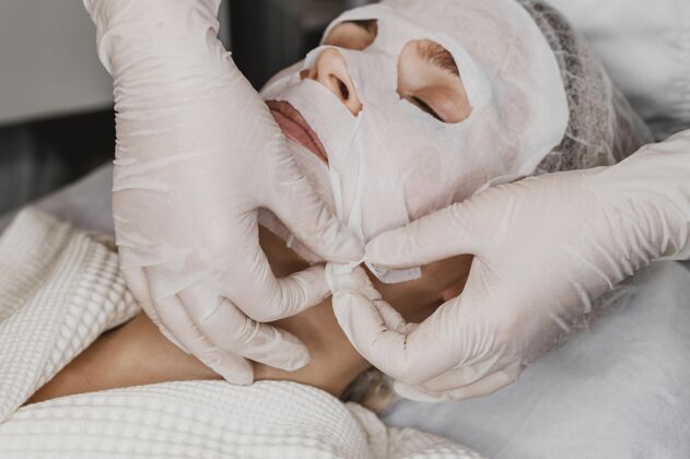 女性年轻漂亮的女人在水疗中心接受皮肤面膜治疗水平美容过程