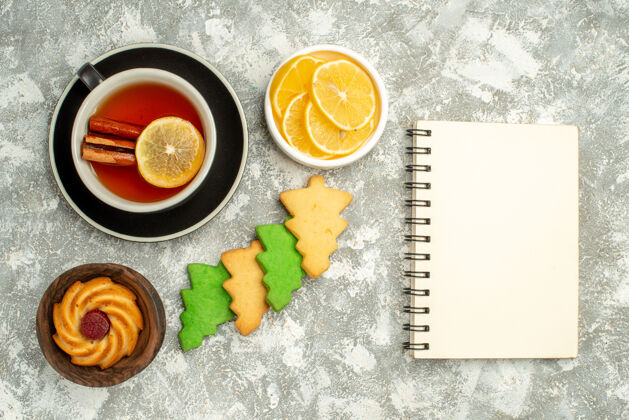 晚餐顶视图茶饼干杯柠檬片笔记本在灰色表面维生素视图柠檬