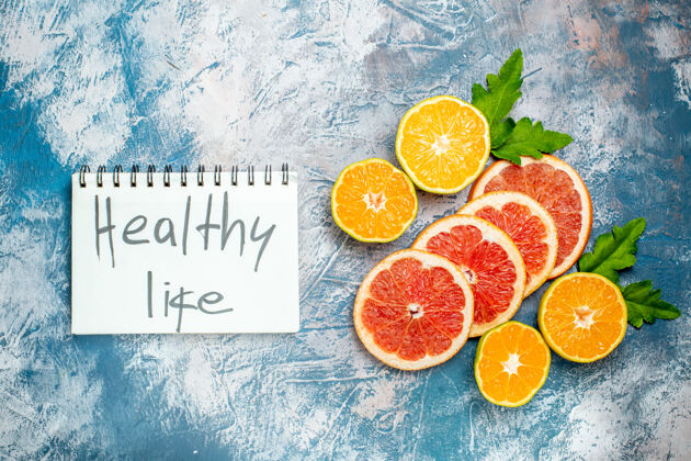 柑橘俯瞰写在笔记本上的健活切橘子和葡萄柚在蓝白色的表面橙子多汁顶部