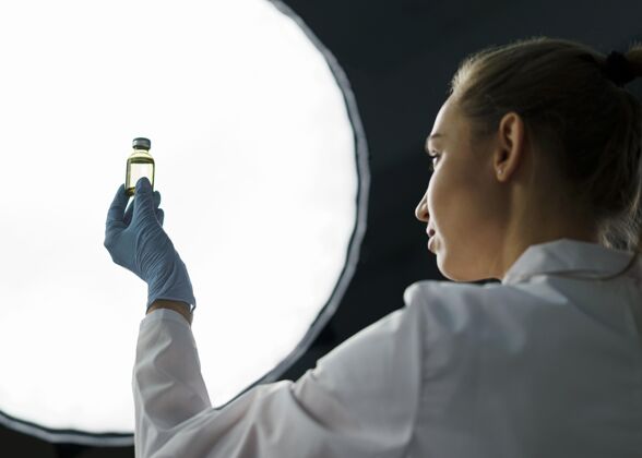 女人实验室里的女研究员手里拿着疫苗瓶旁边的灯实验室技术员发明家瓶子