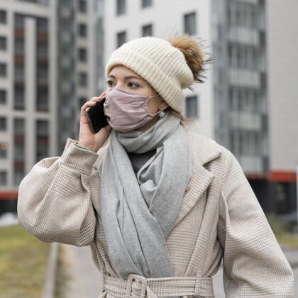 流行病戴着医用口罩的女人在城里打电话病毒公民大流行