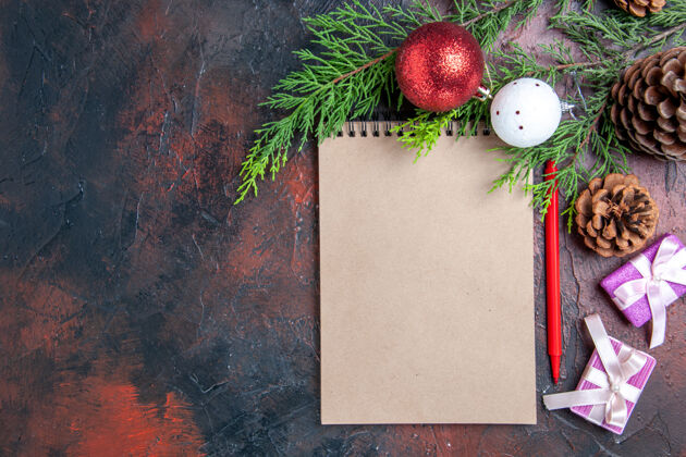 松树顶视图红笔笔记本松树枝圣诞树球玩具和礼品暗红色表面免费空间视图笔记本杉木