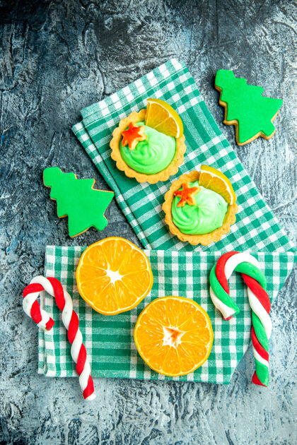切片顶视图切橘子圣诞树糖果小馅饼绿色白色方格厨房毛巾在灰色的桌子上顶部视图柠檬