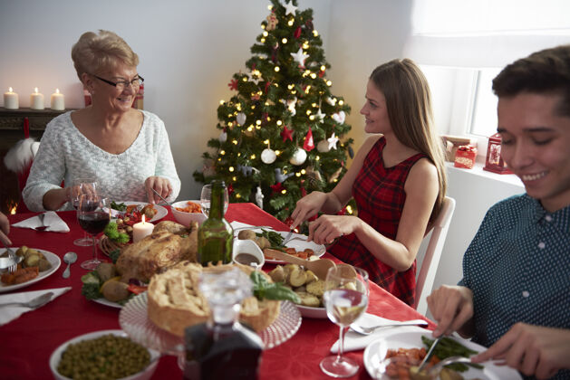 餐厅祖母和她的孙子们在圣诞桌旁桌子吃饭壁炉
