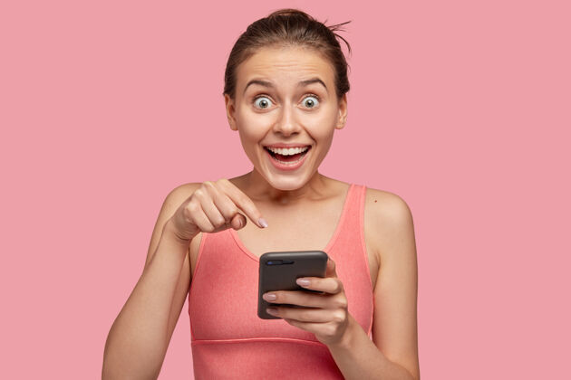 女性正惊讶的年轻女性指着手机屏幕手机照片指向