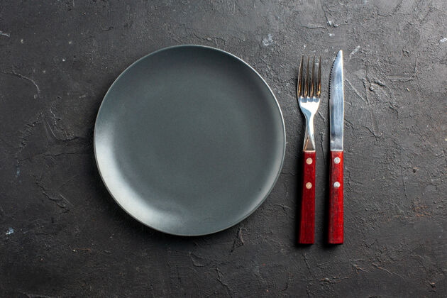 叉子俯视图黑色圆板黑色表面上的刀叉刀炒锅晚餐