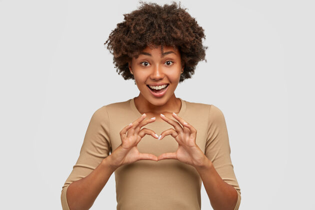 浪漫爱与和平给你善良快乐的年轻美丽的非洲裔美国妇女在胸前展示心形标志展示套头衫非洲